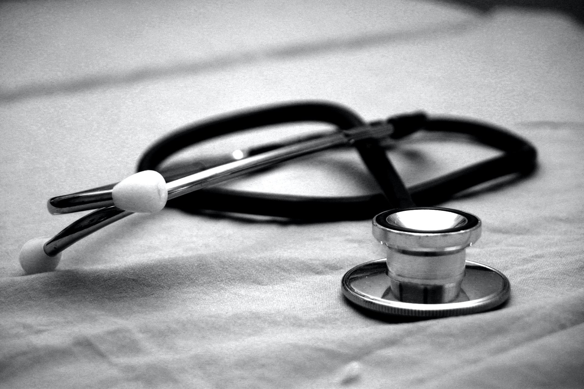black & white image of stethoscope lying on table. Photo by Hush Naidoo on Unsplash